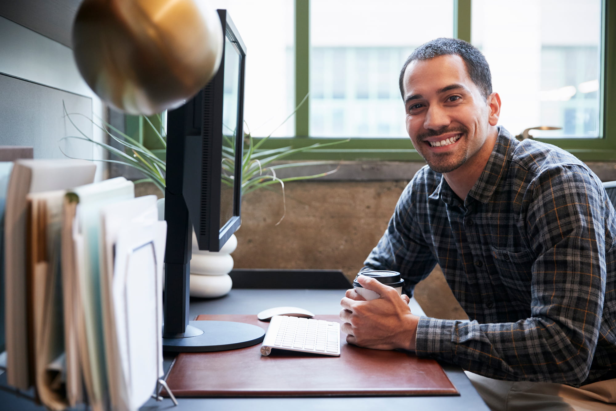 hispanic man at a computer in an office smiling to 2021 08 26 16 13 43 utc