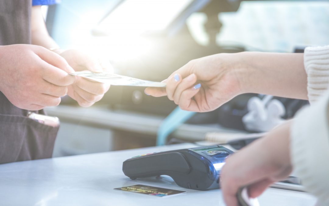 At a bustling Maryland store, a customer hands money to the cashier at the counter, with an Everpayer card reader prominently in the foreground.
